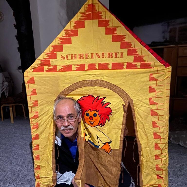 Sven Coorßen schaut aus der offene Tür eines Kinderzelt von der Marke Sioux Sheriff Esber. Auf dem Kinderzelt steht Schreinerei und es gibt ein Motiv des Pumuckls.