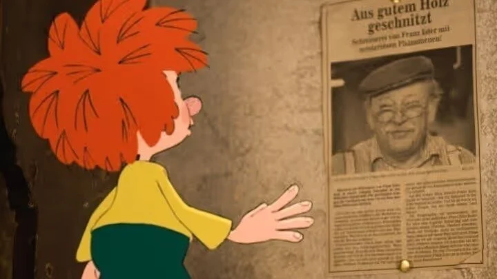 Die Zeichentrickfigur Pumuckl guckt sich eine Announce an, wo Meister Eder zu sehen ist mit dem Titel "Aus gutem Holz geschnitzt".