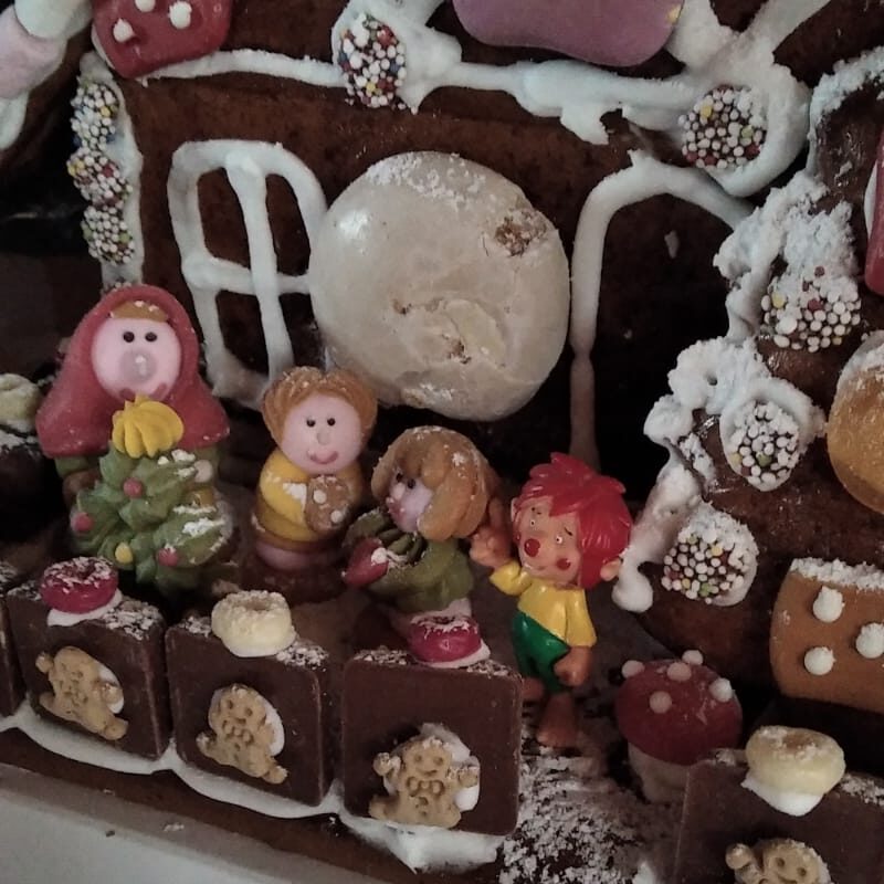 Lebkuchenhaus mit kleinen Figuren, unter anderem einem Pumuckl